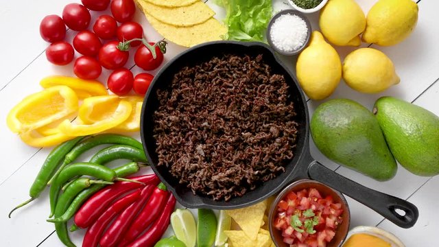 Ingredients for Chili con carne in frying iron pan on white wooden table