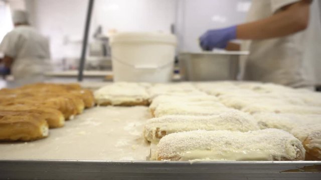 Making and decorating custard cakes with the help of glaze and coconut chips at a confectionery factory, handwork