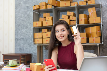 Online business. Beautiful young woman business owner about online business. Successful and happy with the business. Woman holding credit card and Mobile phone. online shopping concept.