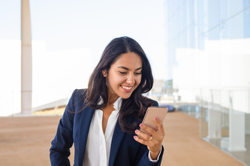 Cheerful businesswoman using smartphone. Beautiful happy young woman in formal wear using mobile phone. Technology concept