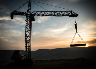 Abstract Industrial background with construction crane silhouette over amazing sunset sky. Tower...
