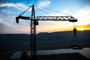 Abstract Industrial background with construction crane silhouette over amazing sunset sky. Tower crane against the evening sky. Industrial skyline