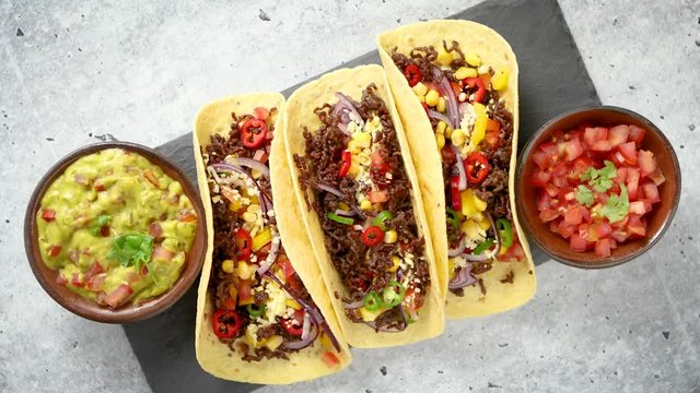 Tasty Mexican meat tacos served with various vegetables and salsa