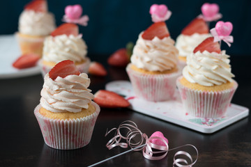 vanilla cupcakes with fresh strawberries on a dark background