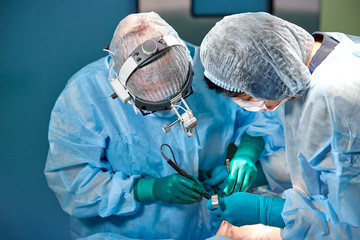 Surgeon and his assistant performing cosmetic surgery on nose in hospital operating room. Nose...