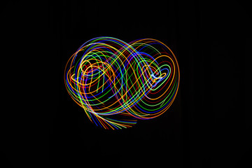 Long exposure photography made with light paint of various colors on a black background, waves, curves and swirls, curvilinear or rounded pattern.