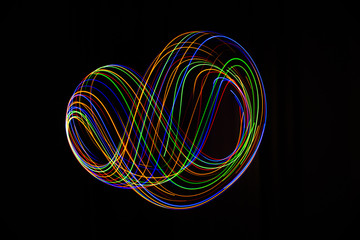 Long exposure photography made with light paint of various colors on a black background, waves, curves and swirls, curvilinear or rounded pattern.
