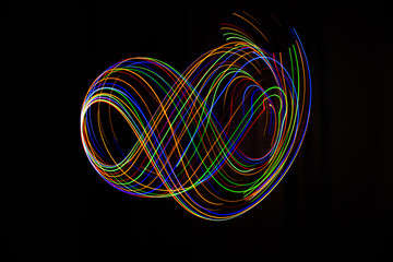 Long exposure photography made with light paint of various colors on a black background, waves, curves and swirls, curvilinear or rounded pattern.