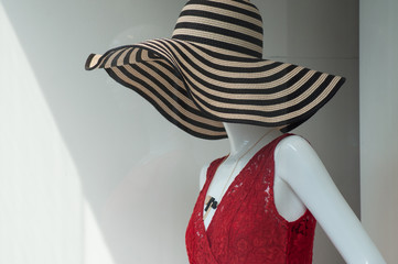 closeup of big summer hat and red dress on mannequin in a fashion store showroom for women