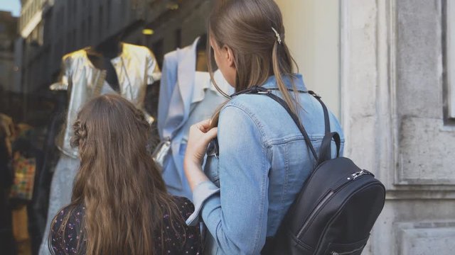 Family looking at shop window of clothing store.