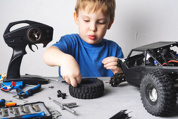 obby radio modeling: a little boy in a blue T-shirt repairing a radio-controlled car buggy with a screwdriver.