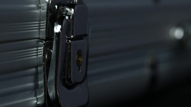 Extreme closeup of male hand closing metal briefcase