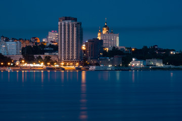 Night View of the city of Khabarovsk from the Amur river. Blue night sky. The night city is brightly lit with lanterns.