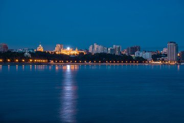 Night View of the city of Khabarovsk from the Amur river. Blue night sky. The night city is brightly lit with lanterns.