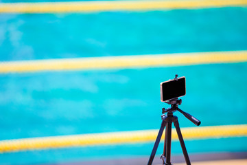 smartphone camera on tripod taking photo swim race competition at  swimming pool