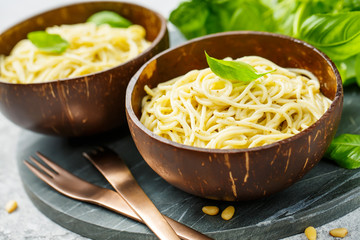 Delicious pasta with pesto sauce served in a bowls of coconut