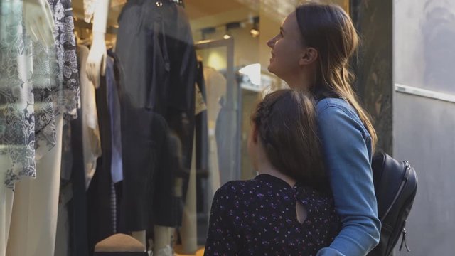Family looking at shop window of clothing store.