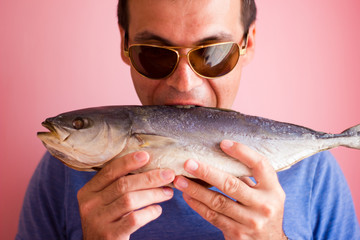Young man with a fish in his hands - salted tuna