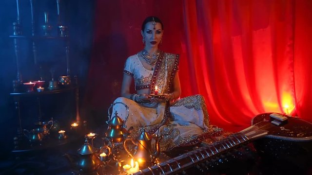 Beautiful young indian woman in traditional Sari clothing and Oriental Jewelry with candle