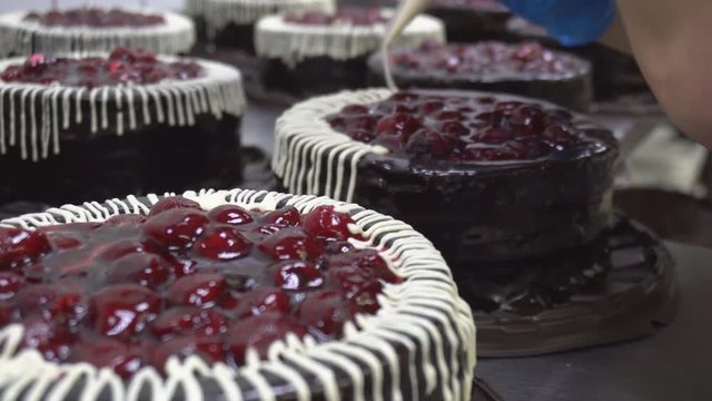 Decorating and making chocolate biscuit cakes with fresh cherry berries in production. Trot's decoration with cream, technology