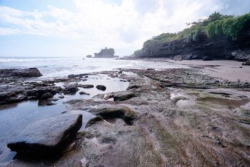 Beautiful balinese landscape. Ocean beach. Ancient hinduism temple Tanah lot on the rock against cloudy sky. Bali Island, Indonesia.