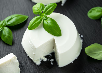 Fresh Ricotta cheese with basil leaf on black rustic table. selected focus
