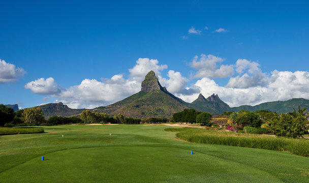 Rempart Mountain seen from a Golf Course on the Indian Island of Mauritius. Blue skies and fluffy white clouds in the background.