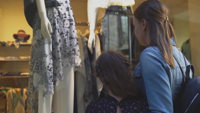 Family looking at shop window of clothing store.
