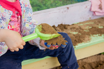 Children play in a sandbox with molds and knives. Sculpting sand figures.