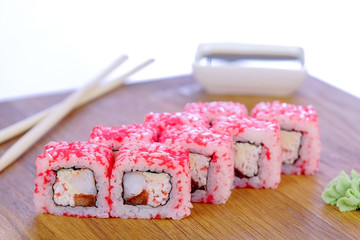Rolls with fish, shrimps and red caviar on top served on wooden board with wasabi and soy sauce