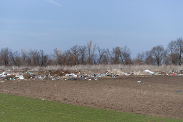 Fototapeta na wymiar Trash on the agriculture field. Ecology problem and big harm to nature.