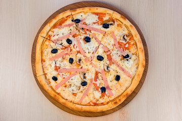 Pizza with bacon and cheese on wooden board on the table. Close-up view