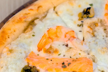 Quarter of slicing pizza with seafood and cheese on wooden board, close-up view