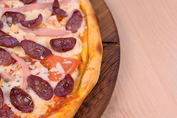 Quarter of pizza with smoked sausage, ham and cheese. Close-up view