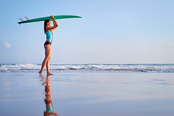 It's time for surfing! Hobby and vacation. Pretty young woman holding surf board on the sea shore.