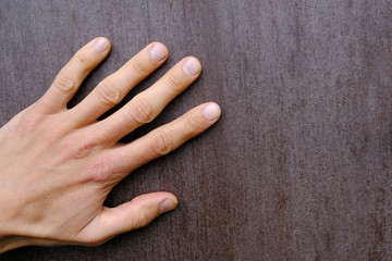 human hand palm on brown wooden surface, texture and background close-up