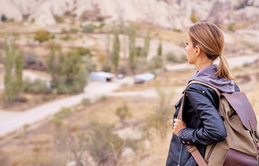 Naklejka na ściany i meble Travel concept. Traveling young woman with backpack enjoying mountains view.