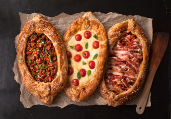 Traditional Turkish baked pide dish. Middle Eastern snacks. Turkish pizza. Three Pides of cheese, meat and bacon. Open pies with different maingame. The view from the top. Copy space. - 279633635