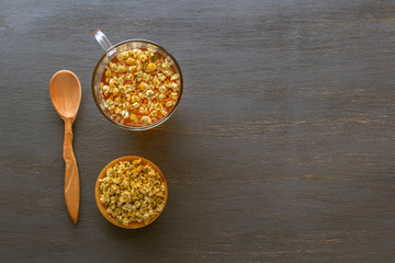 Herbal tea with pharmaceutical chamomile on a gray wooden table. View from above. Copy space.