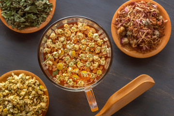 Mug with infusion from a pharmaceutical frame on the background of other medicinal herbs. View from above. Close-up