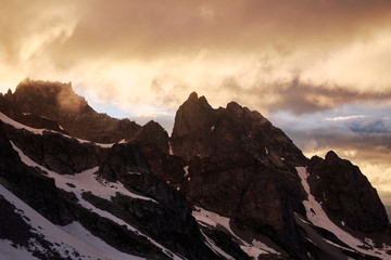 Obraz premium Stunning Sunset in the mountains cloudscape. Silhouette of snowy rock under the dramatic cloudy sky. Sozarukova Top, Caucasian Mountains in Karachay-Cherkessia, Russia.