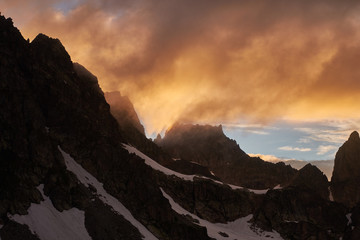 Sunset in the mountains. Silhouette of snowy rock under the dramatic cloudy sky. Caucasian Mountains in Karachay-Cherkessia, Russia.