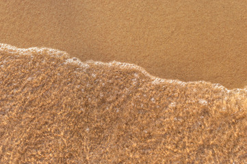 Wave on sandy beach. Top view.