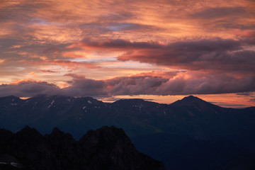 Stunning Sunset in the mountains cloudscape. Silhouette of snowy rock under the dramatic cloudy sky. Caucasian Mountains in Karachay-Cherkessia, Russia.