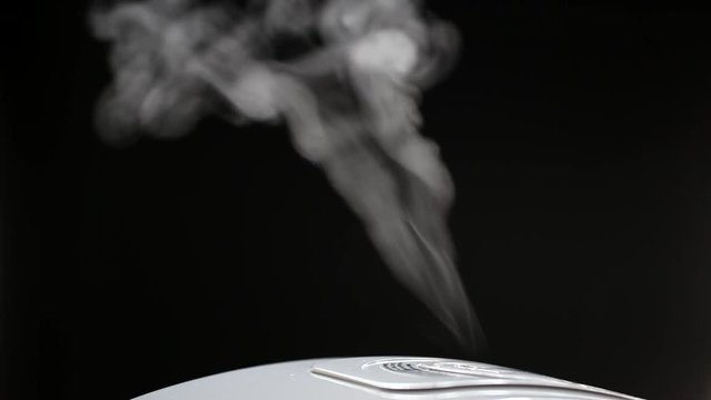 Smoke rising from electronic rice cooker in the kitchen on dark background
