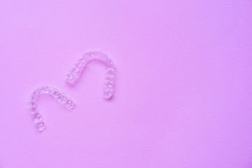 close up top view of dental aligner retainer (invisible) on pink color background for teeth treatment course concept	