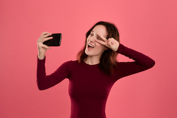 Fototapeta premium Photo of a pretty young brunette woman making selfie with a mobile phone