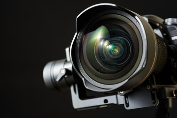 Close-up of wide angle lens in a dsl camera and gimbal stabilizer, with low-key lighting and a...