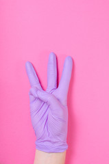 Obraz premium Human hand wearing purple, medical glove shows three fingers
