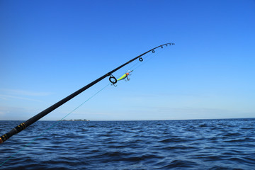 rod with crank bait for catching predatory fish aboard a boat against the blue sea and sky